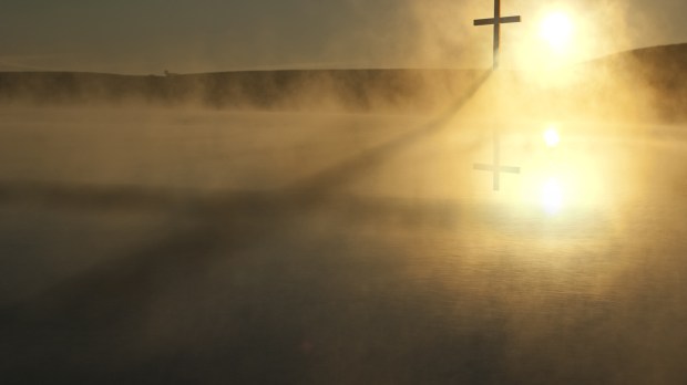 This Sunrise Cross on a misty lake casts a lengthy shadow and reflection on this calm Easter Morning Illustration