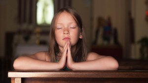CHILD PRAYING IN PEW