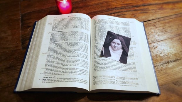 Photo of St. Thérèse of Lisieux on Bible with red candle