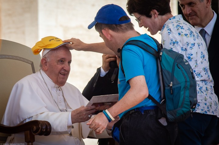 a man puts a hat on Pope Francis had