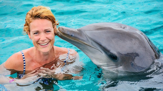 Young-woman-swimming-with-dolpin-at-a-dolfinarium-on-a-sunny-day-shutterstock