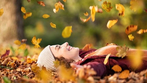 Woman-lying-over-autumn-ground-relaxing-at-park-shutterstock
