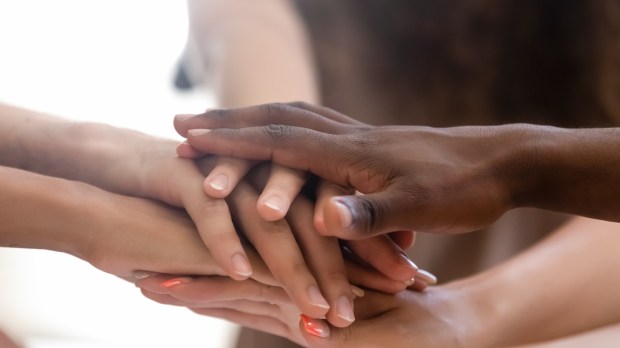 Diverse people group stacked joined hands in pile close up view