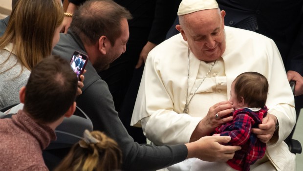 Pope Francis holds a baby at the end of his weekly general audience