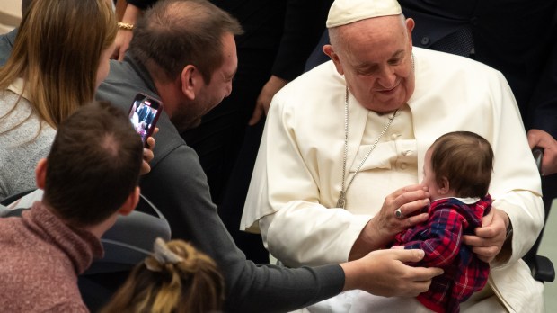 Pope Francis holds a baby at the end of his weekly general audience
