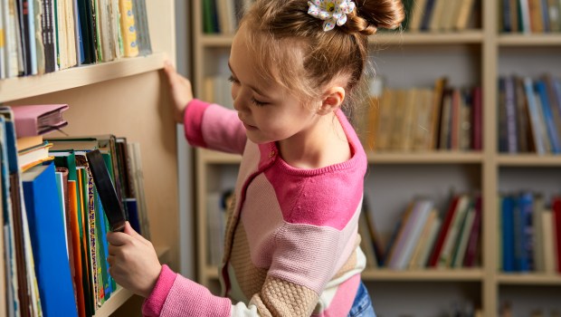 little girl perusing books in library