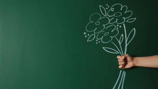woman's hand with drawn flowers in front of chalk board