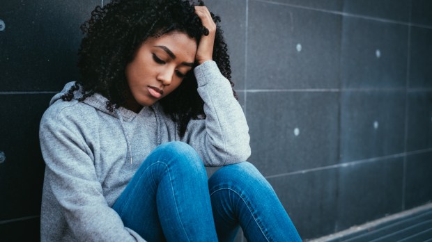 depressed teen girl sitting against wall