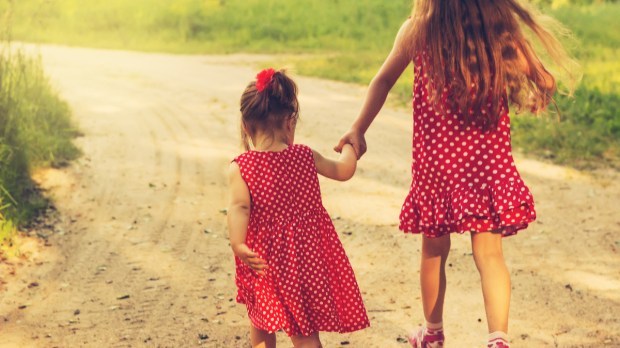 two-sisters-holding-hands-outside