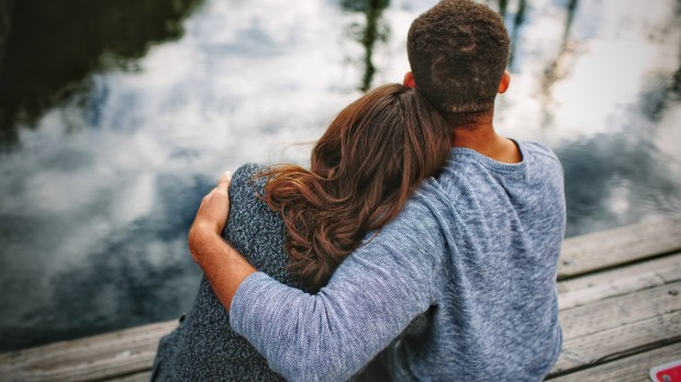 Couple embracing on dock, backs to camera