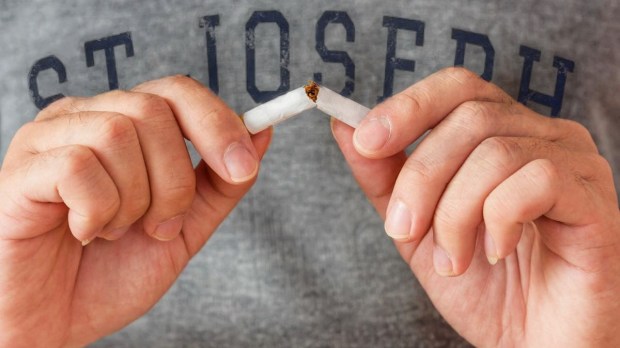 man wearing st. joseph shirt breaking cigarette