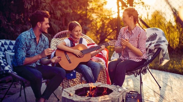 Girl playing guitar with parents clapping outside