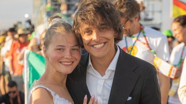A Polish couple wearing a wedding dress and a suit smile at the camera at World Youth Day 2023 in Lisbon