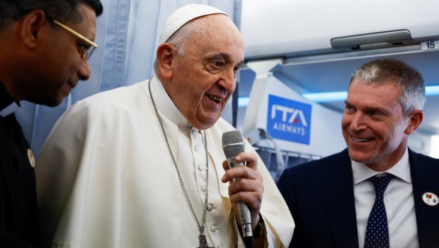Pope Francis talks to journalists aboard his plane before landing at the Figo Maduro air base in Lisbon to attend the World Youth Day