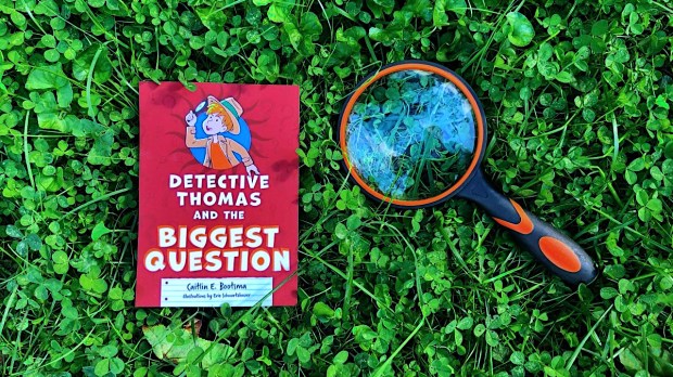 Kids book "Detective Thomas and the Really Big Question" on lawn with magnifying glass