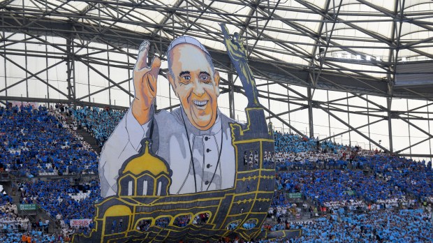 People hold up a huge banner of Pope Francis as he arrives to celebrate mass at the Velodrome stadium in the southern port city of Marseille