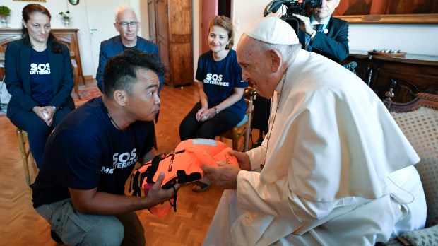 Pope Francis receiving a life jacket from a member of SOS Mediterranee a European NGO that rescue migrants at sea