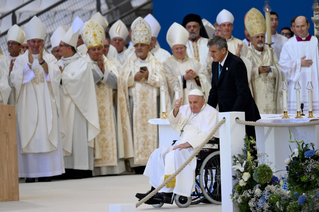 The Pope's aide Sandro Mariotti pushes Pope Francis in his wheelchair as he arrives to celebrate mass at the Velodrome stadium