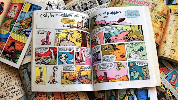 Calvin and Hobbes book on top of many other comic books
