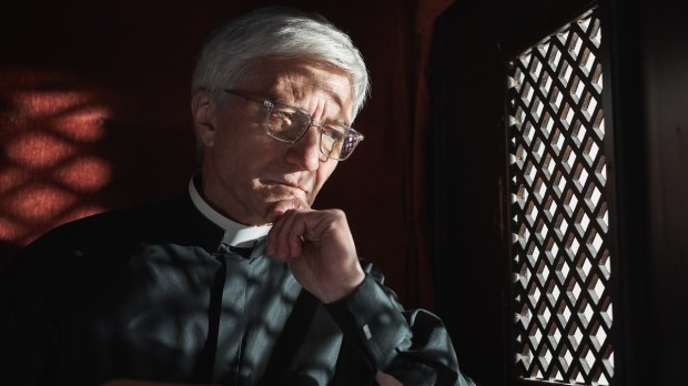 Serious priest in confessional