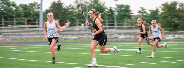Teenage girls running at lacrosse practice