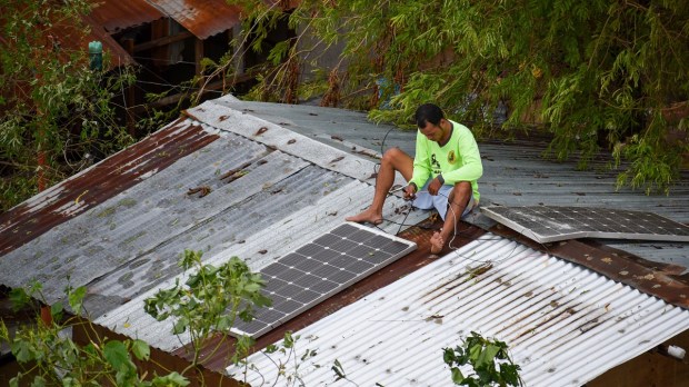 Filipino man setting up solar panels