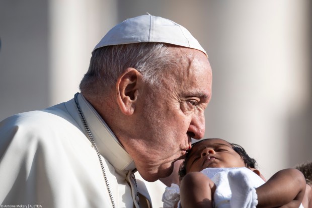 Pope Francis kisses a child as he arrives for his weekly general audience in St. Peter's Square at the Vatican on August 28, 2024