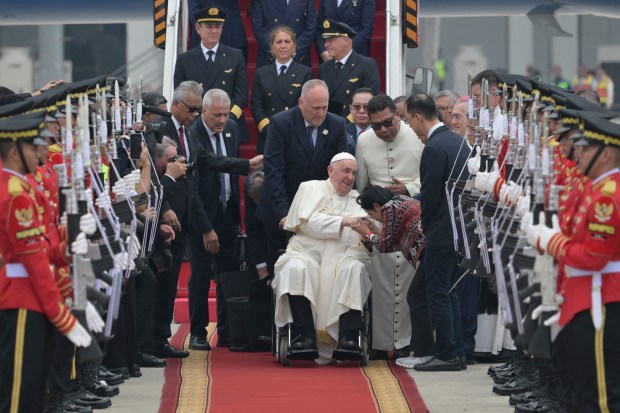 Pope Francis (C, in wheelchair) is welcomed during his arrival at Soekarno-Hatta International Airport in Jakarta on September 3, 2024.